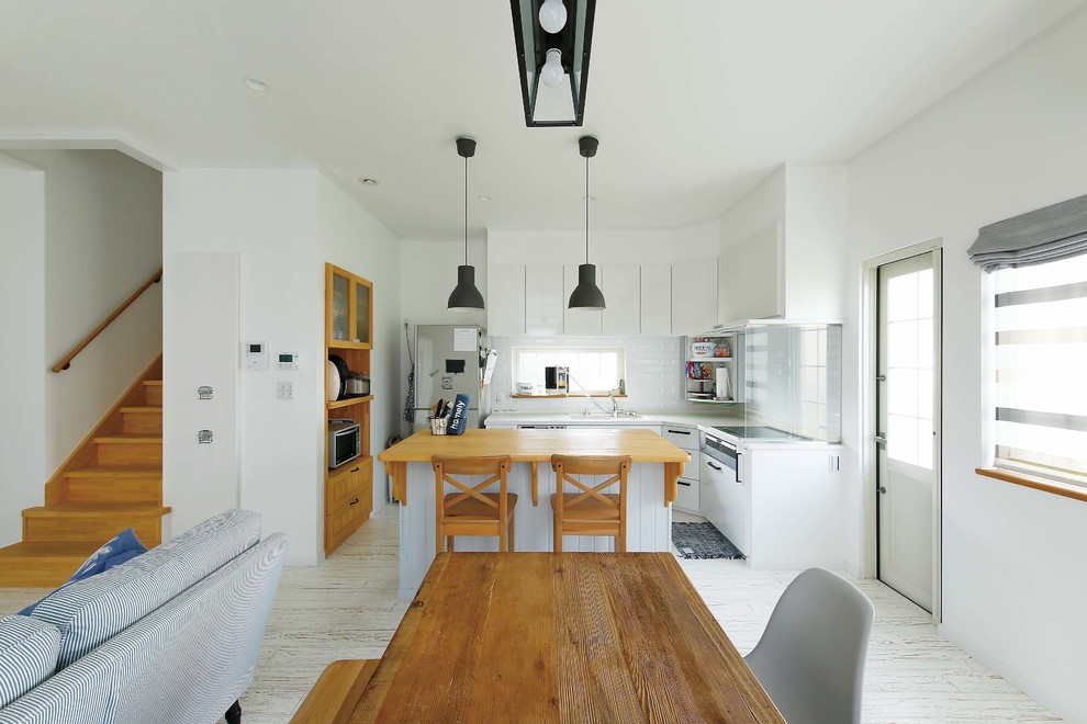 Idee per una sala da pranzo aperta verso il soggiorno stile marinaro con parquet chiaro, pavimento bianco e pareti bianche