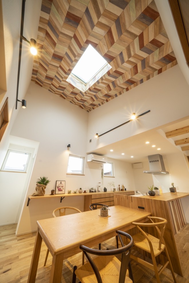 Bild på en mellanstor funkis matplats med öppen planlösning, med vita väggar, ljust trägolv och beiget golv