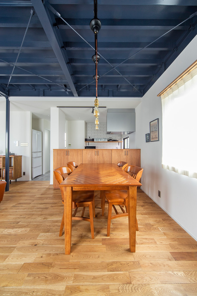 Aménagement d'une salle à manger ouverte sur le salon industrielle de taille moyenne avec un mur blanc, un sol en bois brun et aucune cheminée.