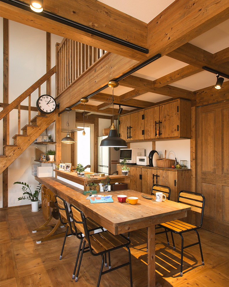 Inspiration pour une salle à manger ouverte sur le salon rustique avec un mur blanc, un sol en bois brun et un sol marron.