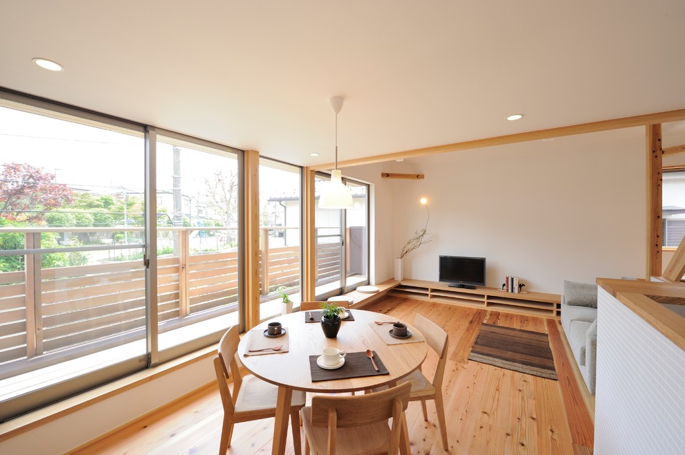 Idée de décoration pour une salle à manger ouverte sur le salon nordique avec un mur blanc et un sol en bois brun.