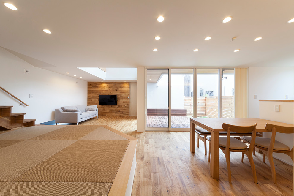 Cette image montre une salle à manger minimaliste avec un mur blanc et un sol marron.