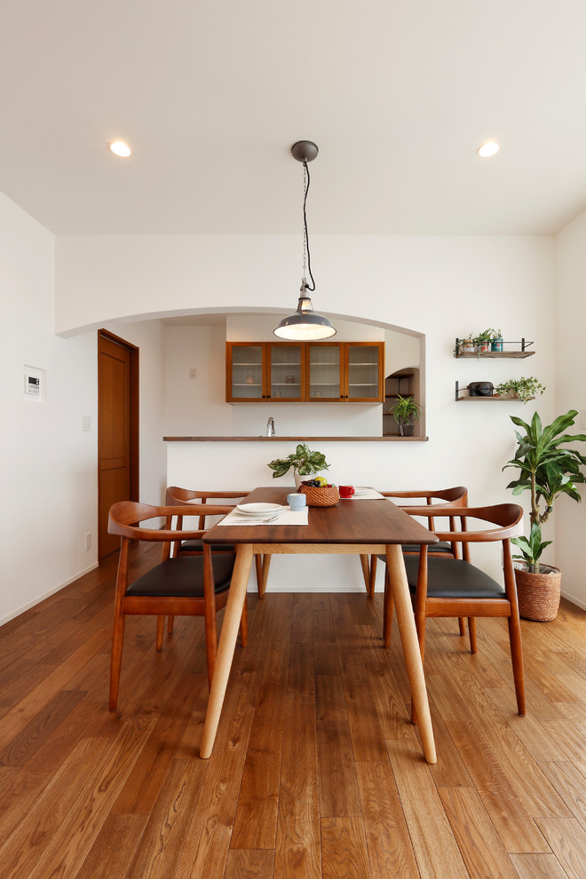 Стильный дизайн: гостиная-столовая в восточном стиле с белыми стенами, паркетным полом среднего тона и коричневым полом - последний тренд