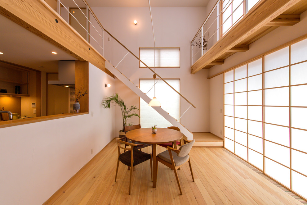 Offenes Asiatisches Esszimmer mit weißer Wandfarbe, hellem Holzboden und braunem Boden in Yokohama