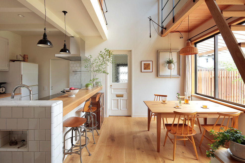 Diseño de comedor nórdico abierto con paredes blancas, suelo de madera en tonos medios y suelo marrón