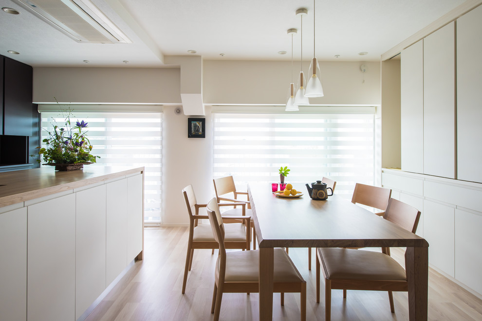 Immagine di una sala da pranzo aperta verso il soggiorno moderna di medie dimensioni con pareti bianche, pavimento in laminato e pavimento beige