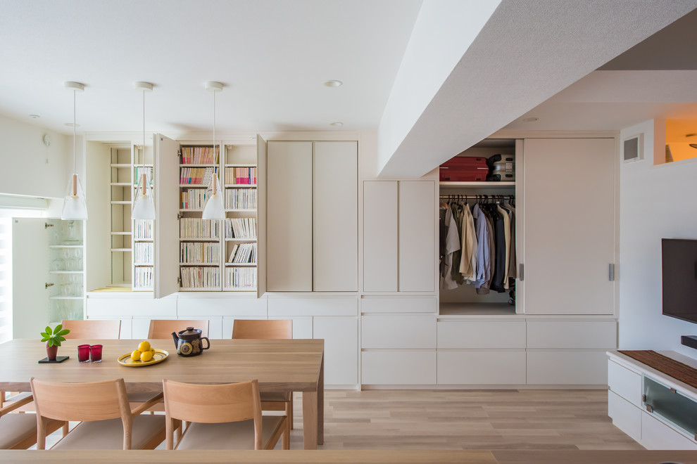 Ispirazione per una sala da pranzo aperta verso il soggiorno minimalista di medie dimensioni con pareti bianche, pavimento in laminato e pavimento beige