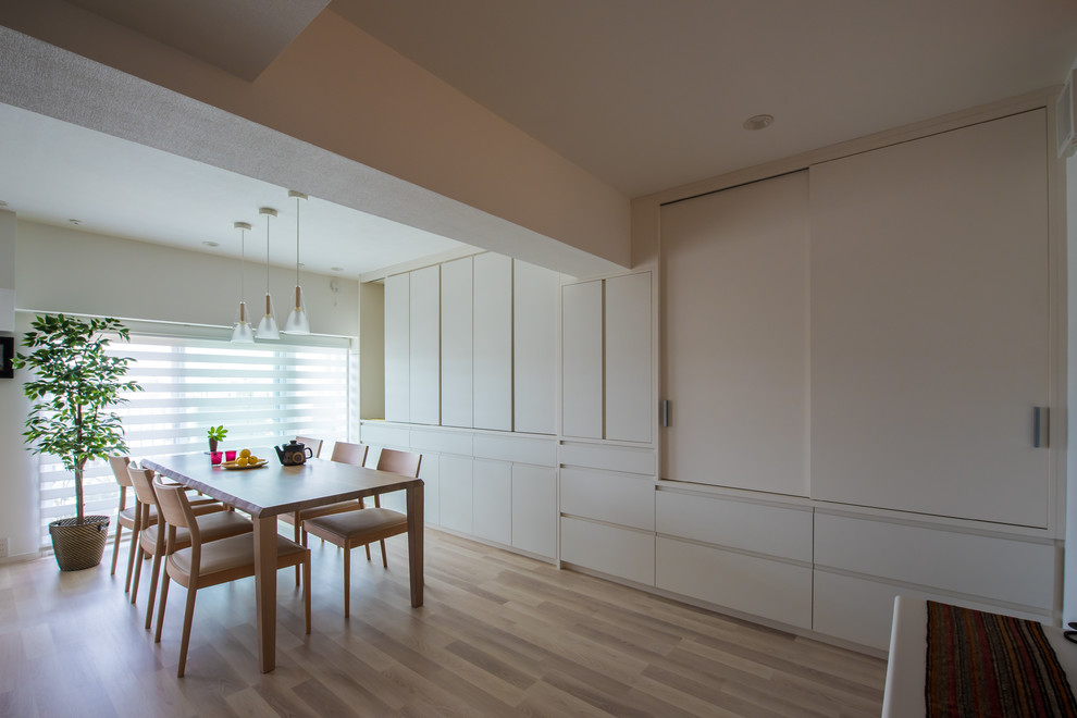 Foto de comedor minimalista de tamaño medio abierto con paredes blancas, suelo laminado y suelo beige
