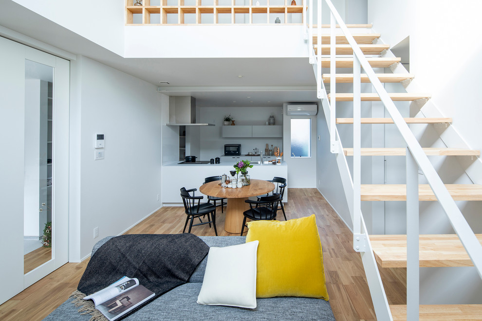 Esempio di una sala da pranzo aperta verso il soggiorno scandinava con pavimento in legno massello medio, pareti bianche e pavimento marrone