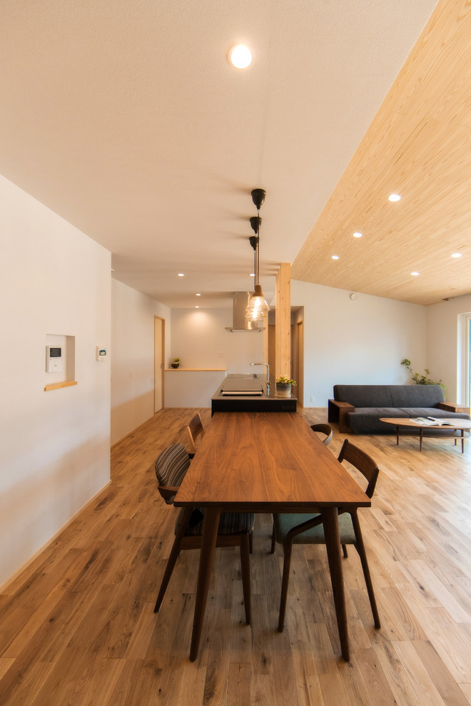 Ejemplo de comedor minimalista grande con paredes blancas y suelo de madera clara