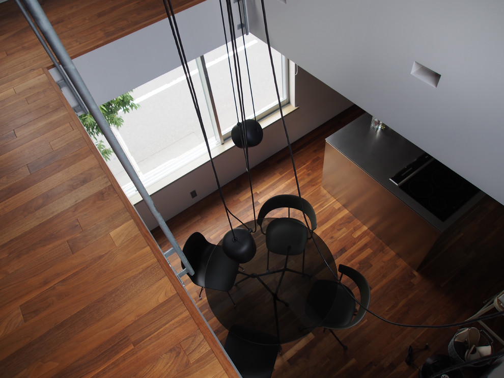 Cette image montre une salle à manger ouverte sur la cuisine design avec un mur gris, parquet foncé et un sol marron.