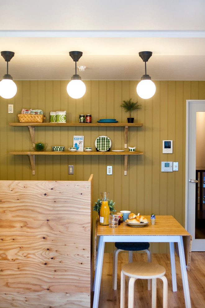 Immagine di una piccola sala da pranzo nordica con pareti gialle, pavimento in legno massello medio e pavimento marrone