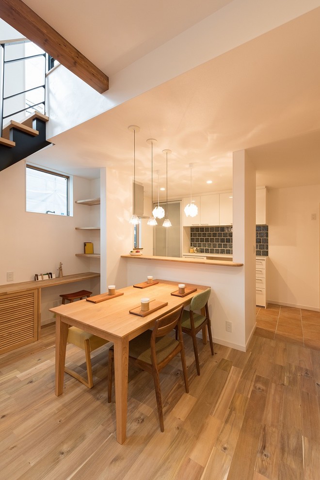 Idee per una sala da pranzo aperta verso la cucina etnica con pareti bianche, pavimento in legno massello medio e pavimento beige