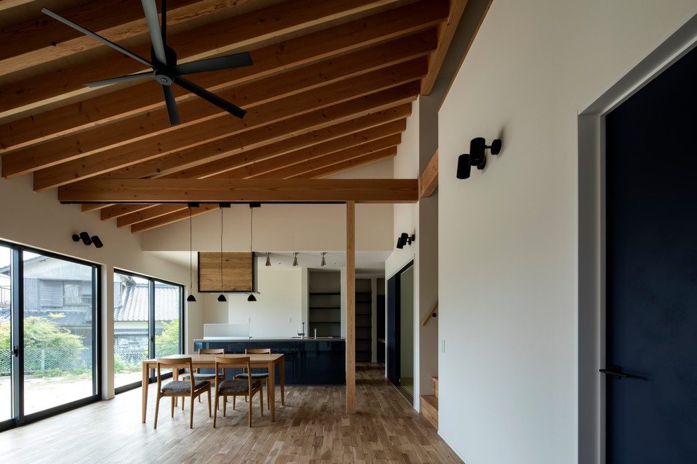 Inspiration pour une salle à manger minimaliste de taille moyenne avec un mur blanc, un sol en bois brun, aucune cheminée et un sol marron.