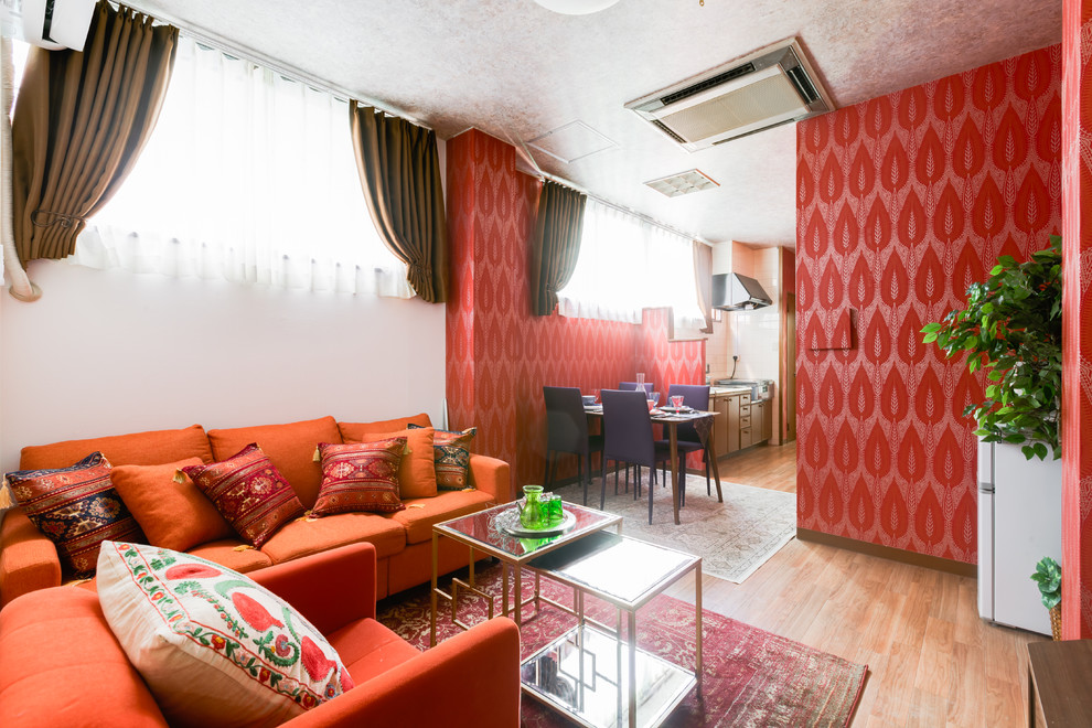 На фото: гостиная-столовая в восточном стиле с красными стенами, паркетным полом среднего тона и коричневым полом