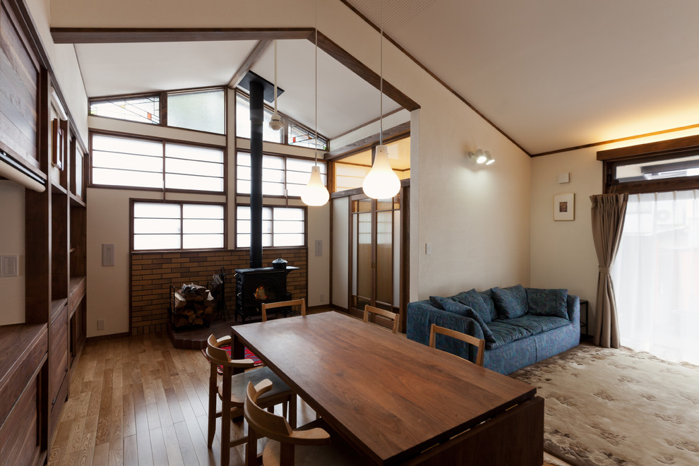 Immagine di una sala da pranzo aperta verso il soggiorno etnica con pareti bianche, pavimento in legno massello medio e pavimento marrone