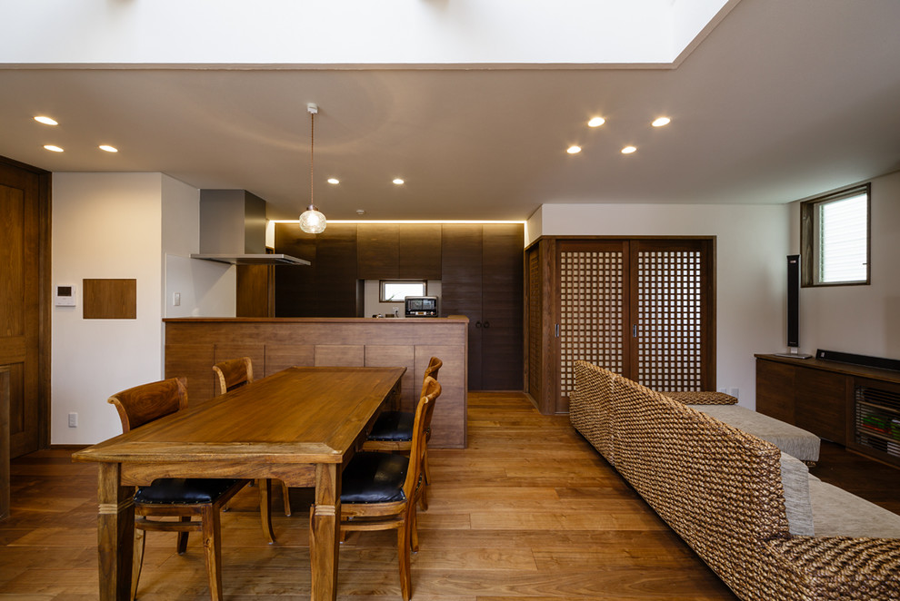 Idéer för en asiatisk matplats med öppen planlösning, med vita väggar, mellanmörkt trägolv och brunt golv