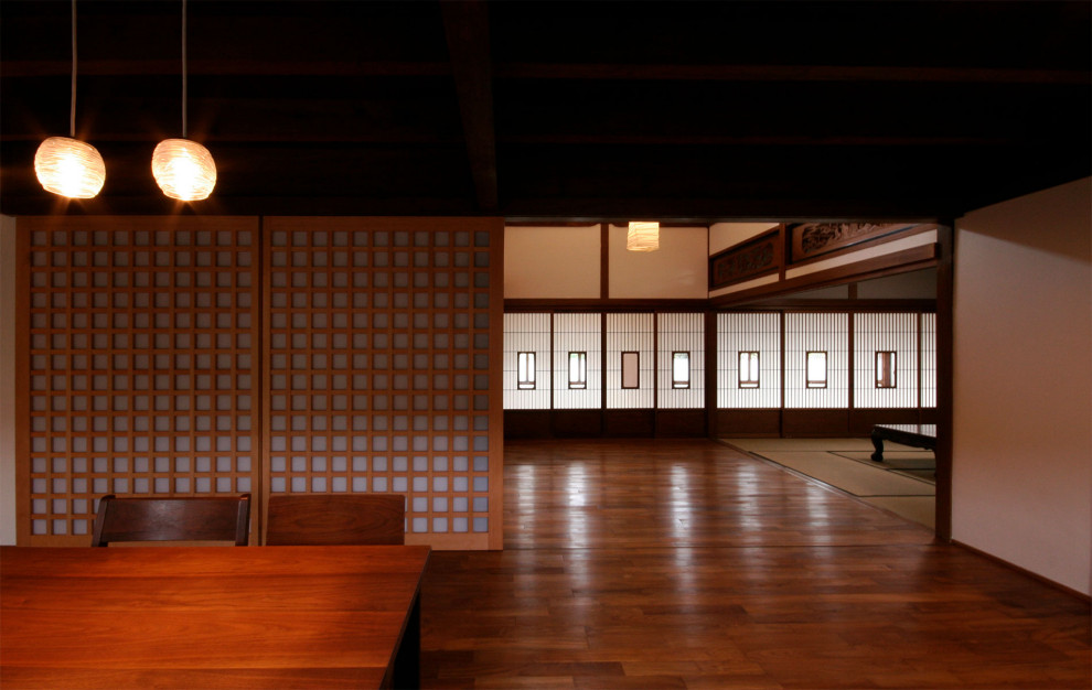 Example of a large zen dark wood floor and brown floor dining room design in Other with brown walls