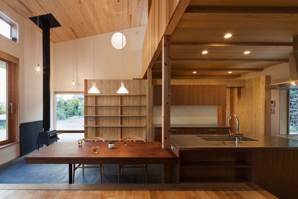 Idée de décoration pour une salle à manger asiatique avec un mur blanc, un sol en bois brun et un poêle à bois.