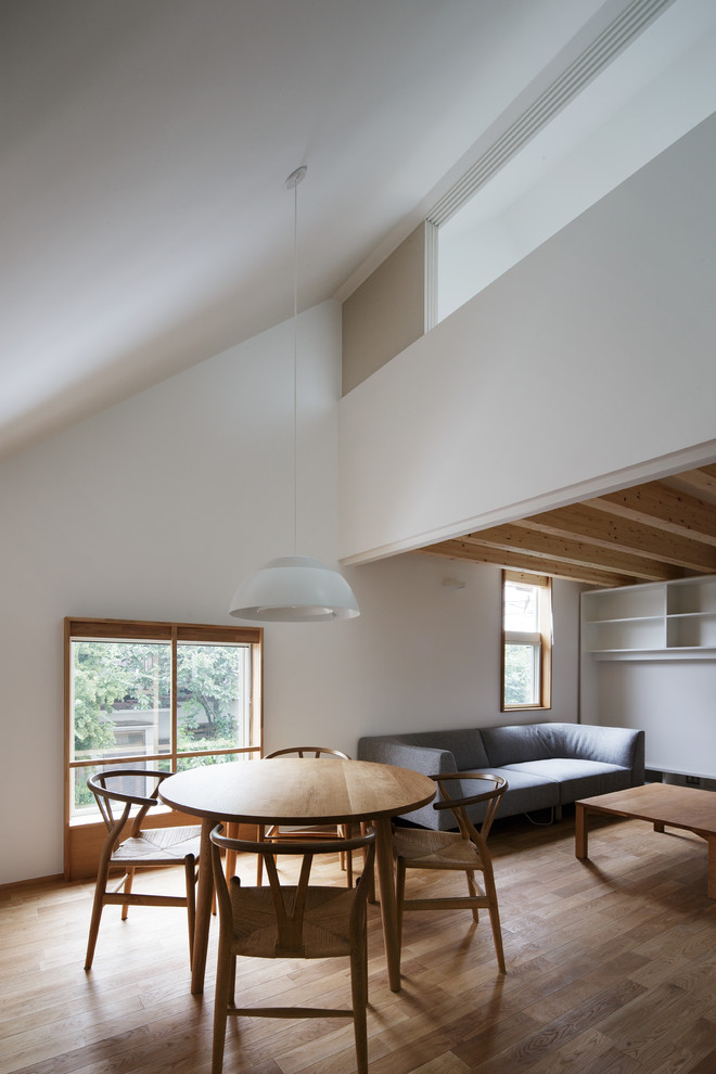 Idée de décoration pour une salle à manger ouverte sur le salon minimaliste avec un mur blanc, un sol en bois brun et un sol marron.
