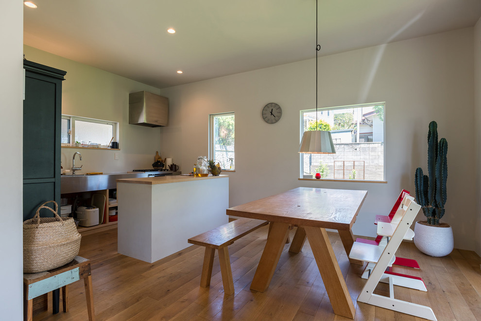 Idée de décoration pour une salle à manger ouverte sur la cuisine marine avec un mur blanc et un sol en bois brun.