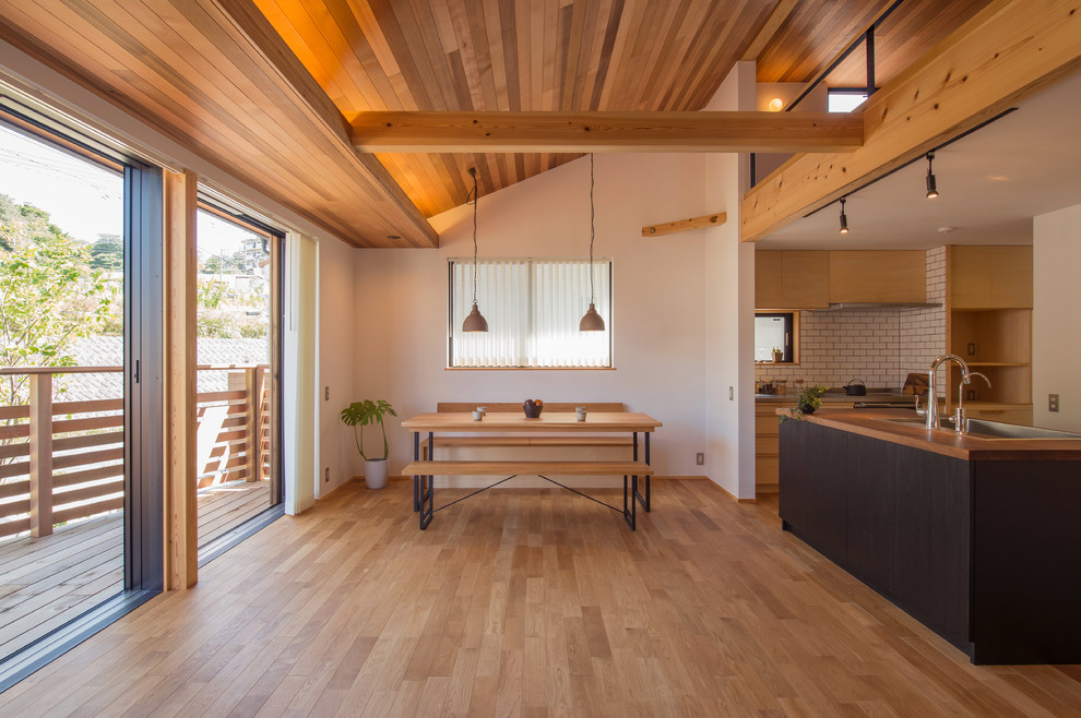 Idée de décoration pour une salle à manger asiatique avec un mur blanc, un sol en bois brun et un sol marron.