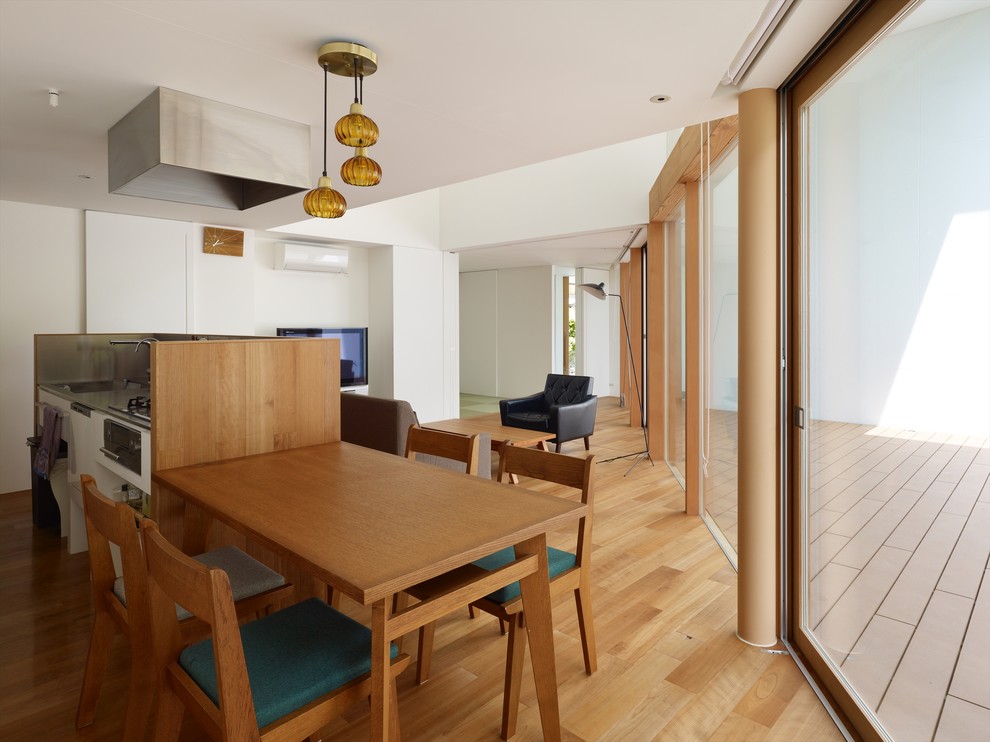 Idée de décoration pour une salle à manger minimaliste de taille moyenne avec un mur blanc, un sol en bois brun, aucune cheminée et un sol orange.