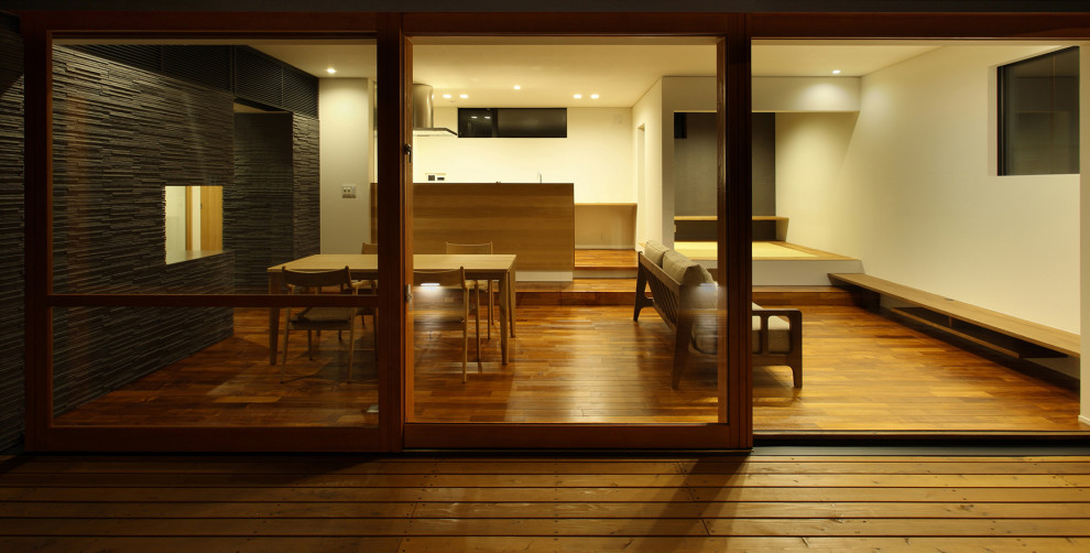 Modelo de comedor moderno grande abierto con paredes beige, suelo de madera oscura y suelo marrón