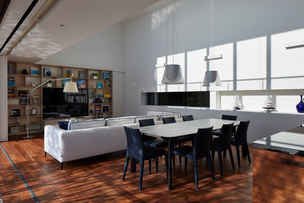 Immagine di una sala da pranzo aperta verso il soggiorno minimal di medie dimensioni con pareti bianche, pavimento in legno massello medio e nessun camino