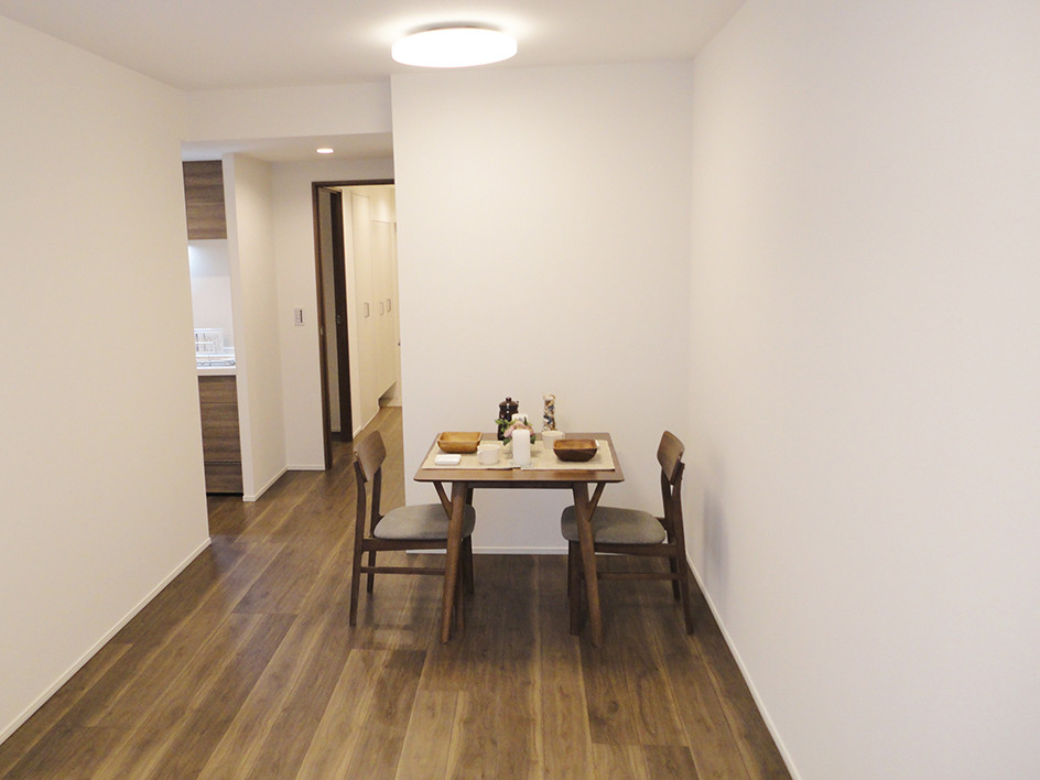 Foto di una sala da pranzo aperta verso il soggiorno moderna con pareti bianche, pavimento in compensato e pavimento marrone