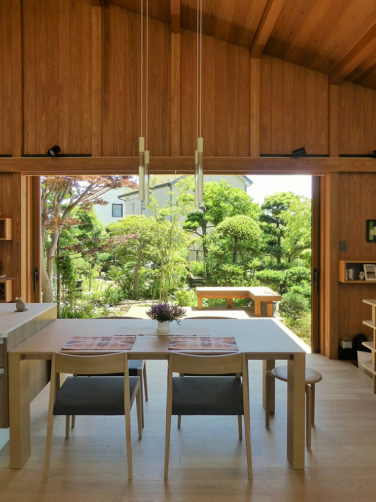 Immagine di una sala da pranzo aperta verso il soggiorno etnica con pareti marroni, parquet chiaro e pavimento beige