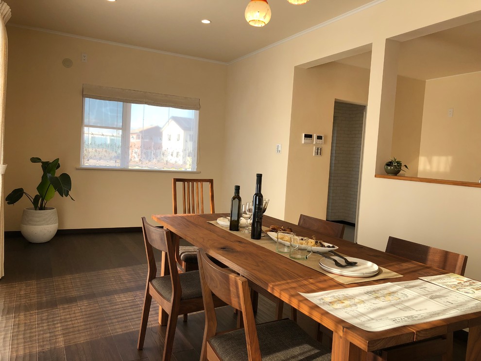 Idée de décoration pour une salle à manger ouverte sur le salon nordique avec un mur beige, parquet foncé, une cheminée standard, un manteau de cheminée en béton et un sol marron.