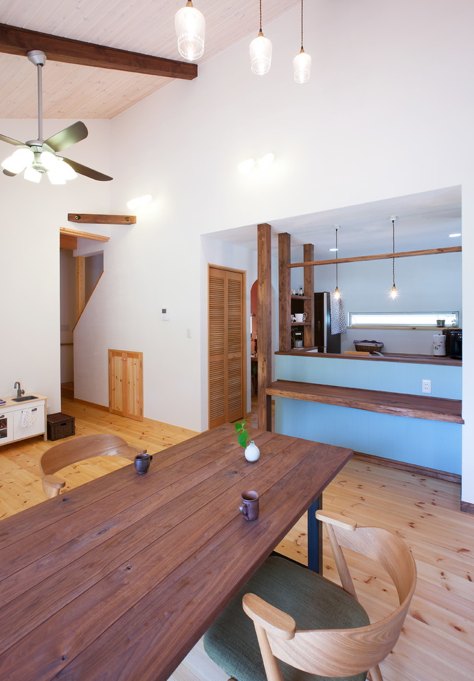Immagine di una sala da pranzo aperta verso il soggiorno etnica con pareti bianche, parquet chiaro e pavimento marrone