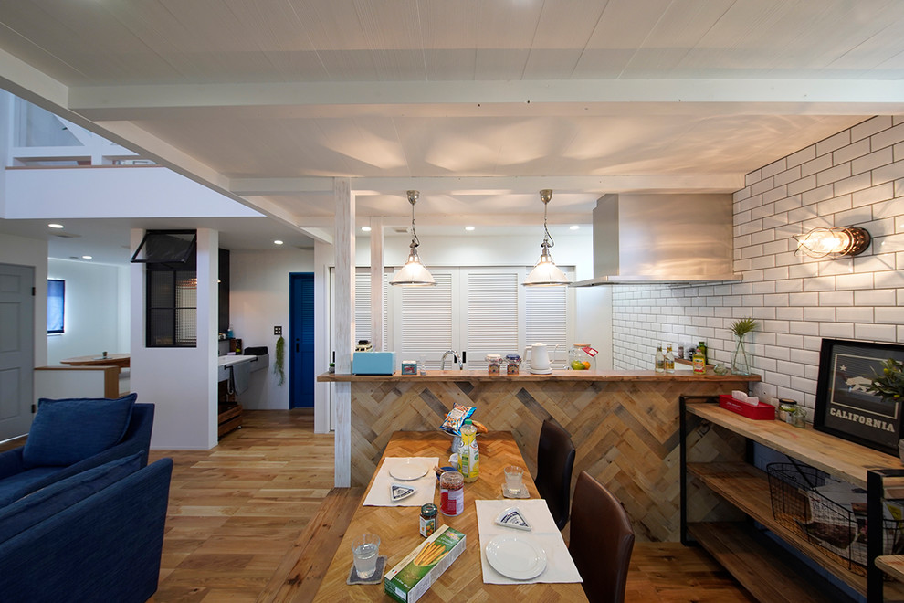 Foto di una sala da pranzo aperta verso il soggiorno stile marino con pareti bianche, pavimento in legno massello medio e pavimento marrone