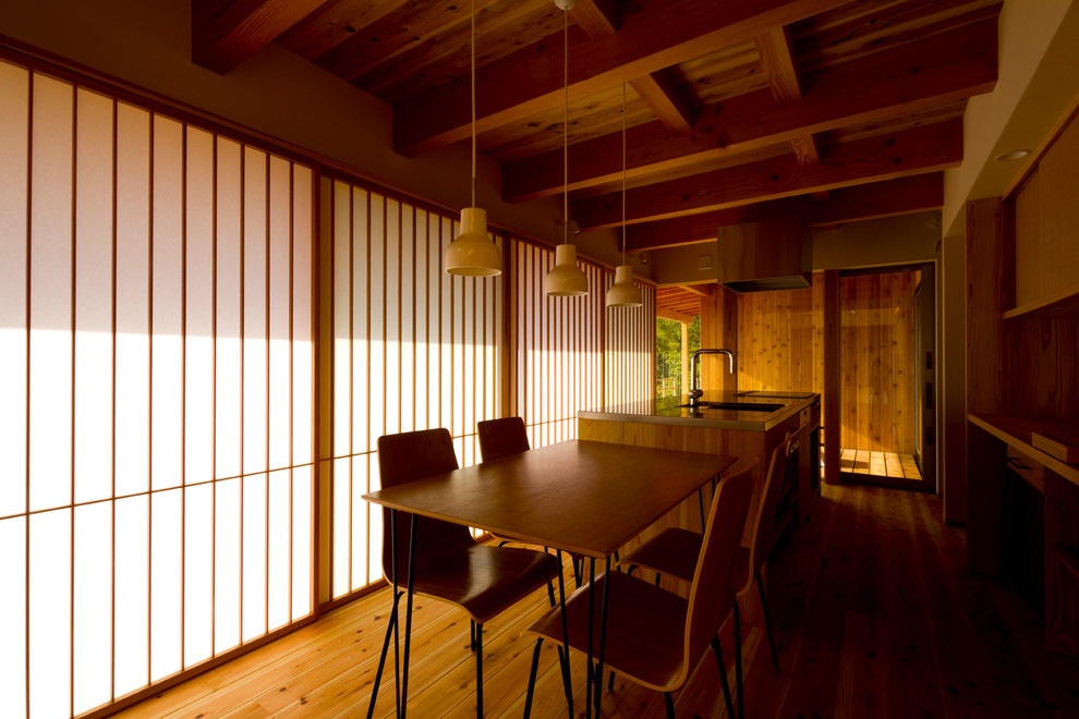 Immagine di una sala da pranzo aperta verso la cucina contemporanea con pavimento in legno massello medio