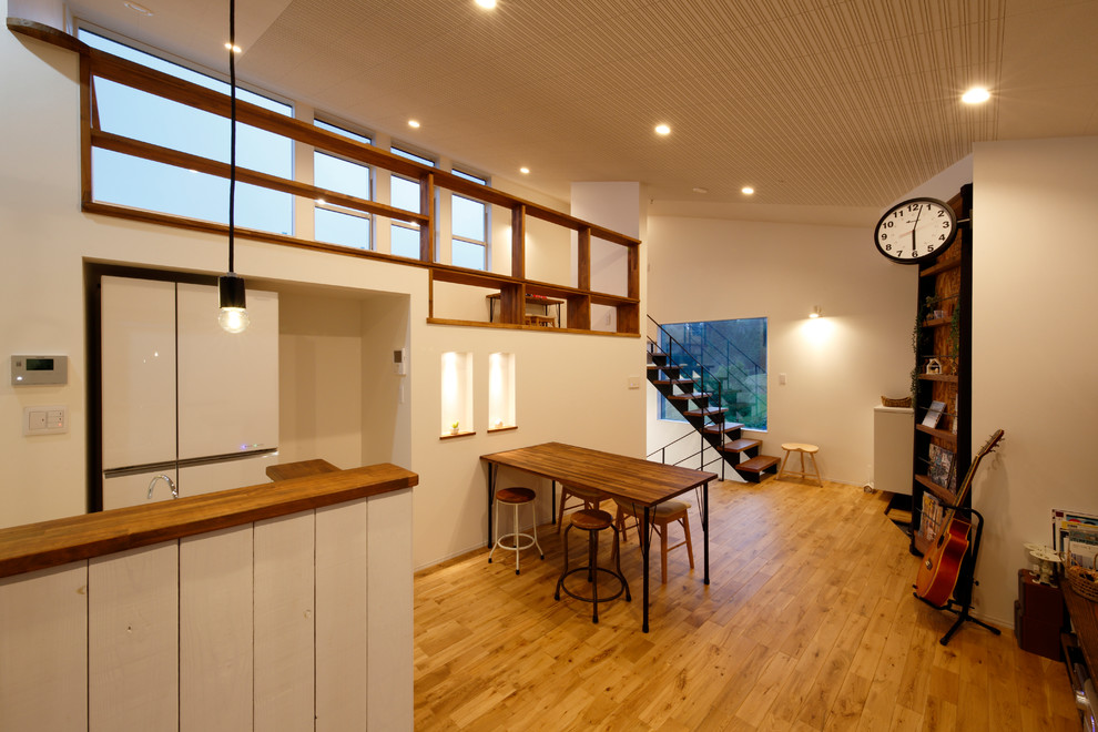 Réalisation d'une salle à manger ouverte sur le salon nordique avec un sol en bois brun, un mur blanc et un sol marron.