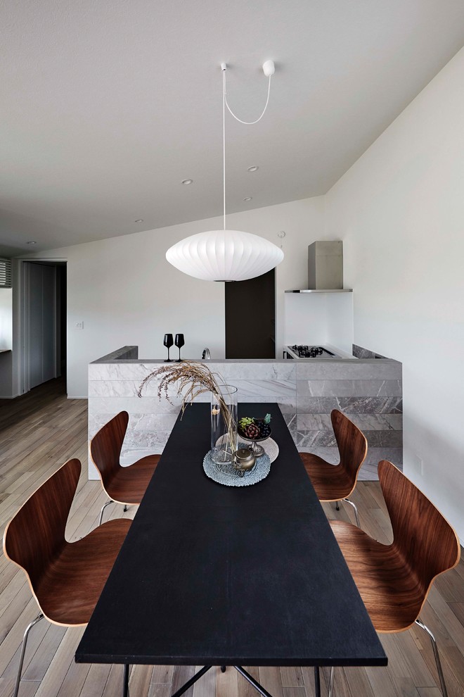 На фото: столовая в стиле модернизм с белыми стенами, деревянным полом и бежевым полом с