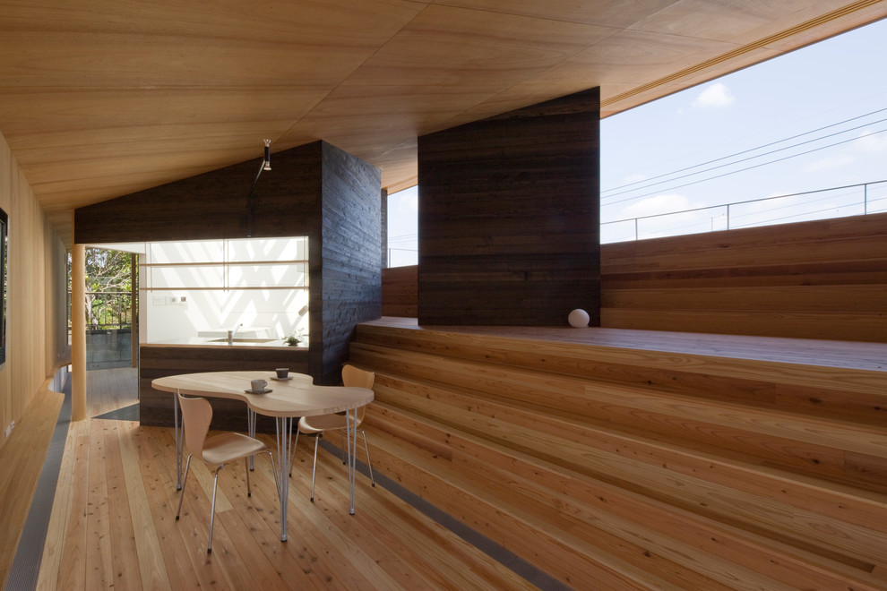 Immagine di una sala da pranzo aperta verso il soggiorno etnica con pareti marroni, parquet chiaro e pavimento marrone
