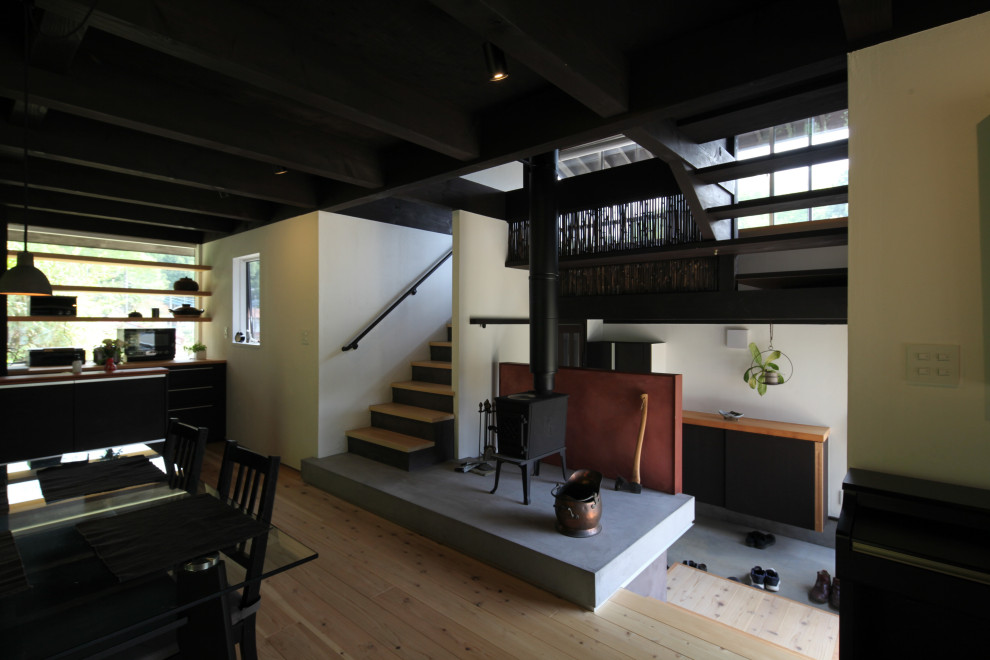 Offenes, Mittelgroßes Rustikales Esszimmer mit weißer Wandfarbe, hellem Holzboden, Kaminofen, verputzter Kaminumrandung und freigelegten Dachbalken in Tokio Peripherie