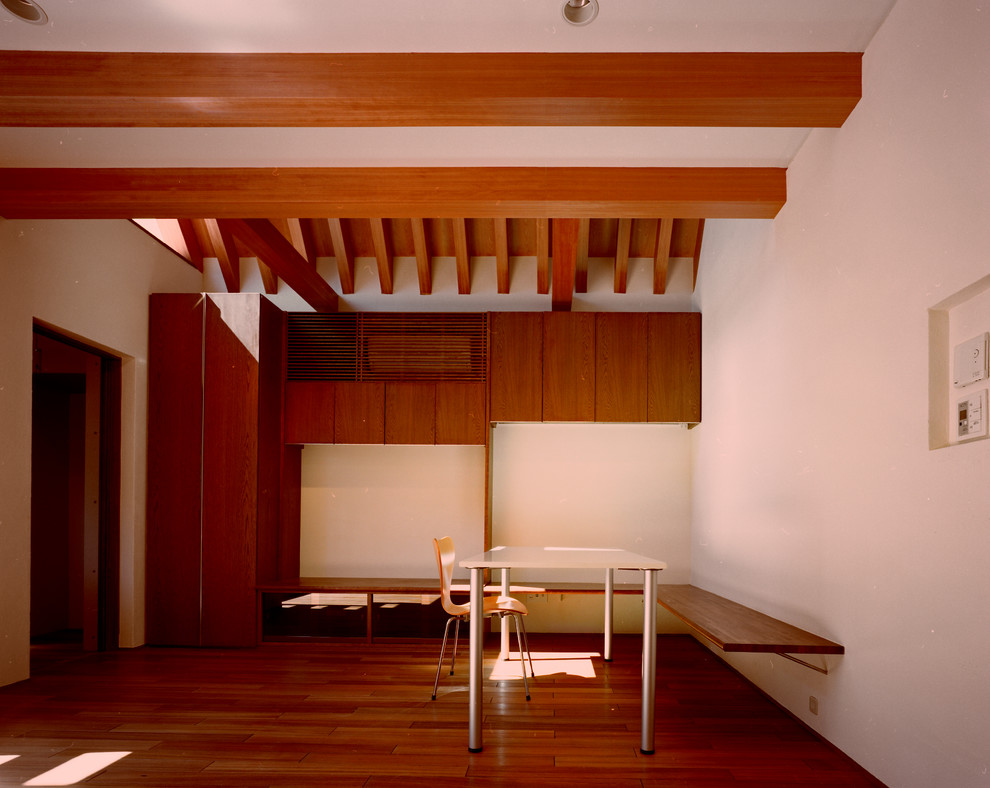 Ejemplo de comedor moderno pequeño abierto sin chimenea con paredes blancas, suelo de madera en tonos medios, marco de chimenea de yeso y suelo marrón