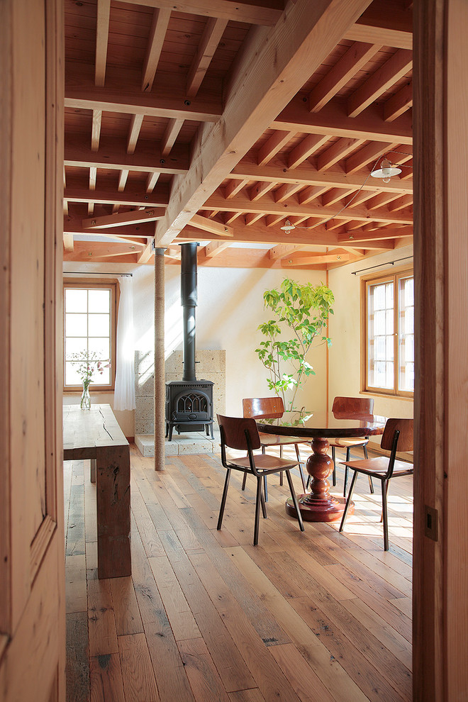 Inspiration pour une salle à manger rustique avec un poêle à bois et un manteau de cheminée en pierre.