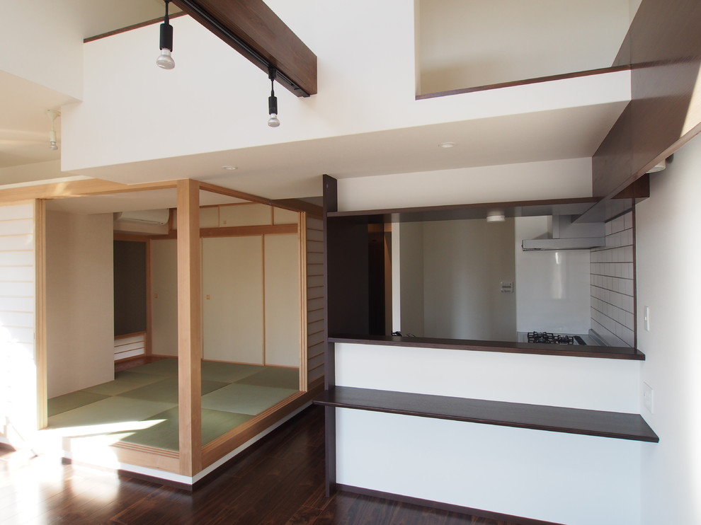 Idee per una sala da pranzo aperta verso la cucina minimalista con pareti bianche, parquet scuro e pavimento marrone