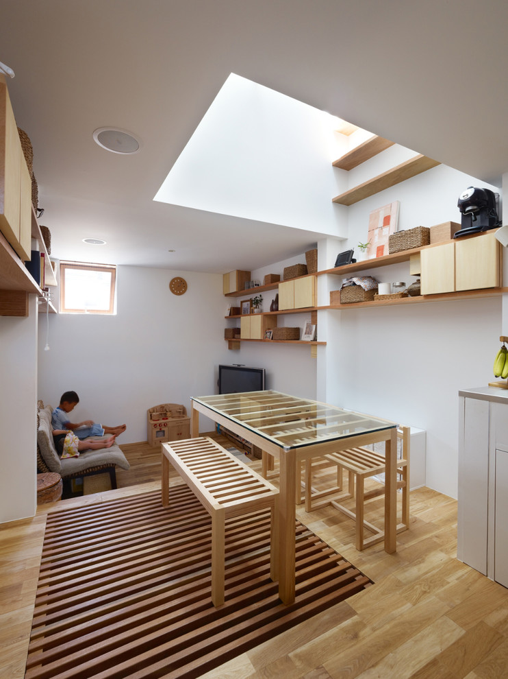 Cette image montre une petite salle à manger design avec un mur blanc, un sol en bois brun et un sol marron.