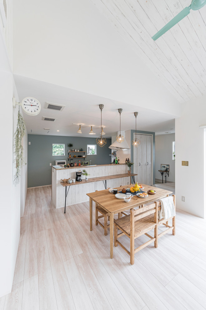 Foto di una sala da pranzo aperta verso la cucina etnica di medie dimensioni con pareti bianche, parquet chiaro e pavimento beige