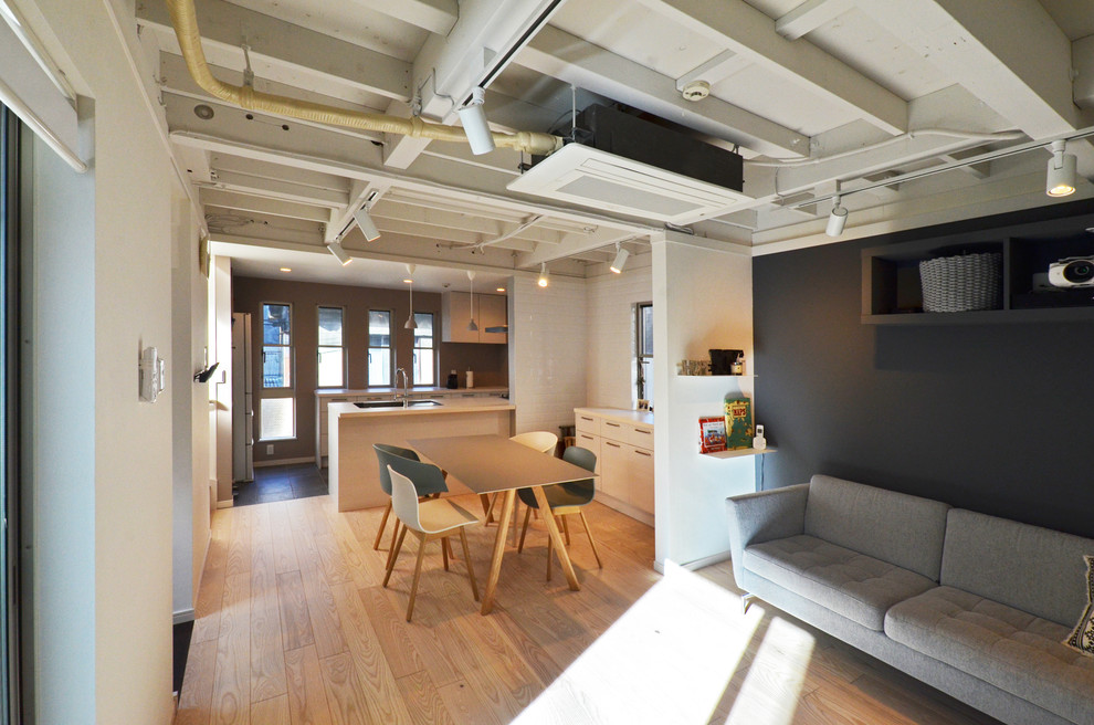 Offenes Industrial Esszimmer mit braunem Holzboden, beigem Boden und bunten Wänden in Tokio