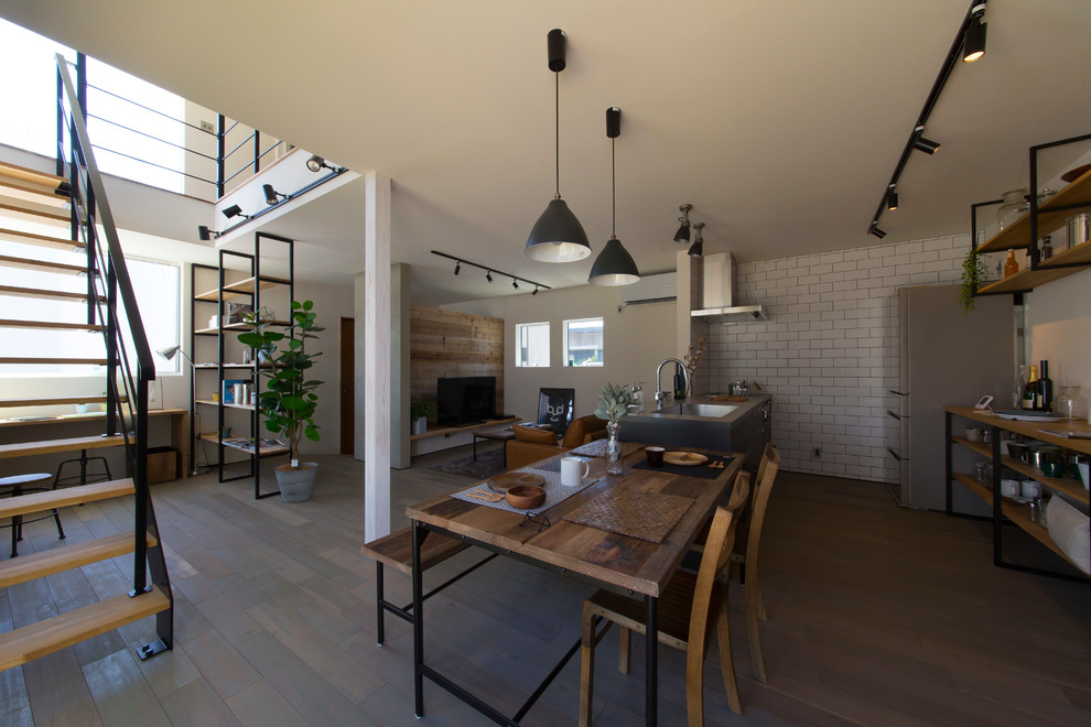 Foto di una sala da pranzo aperta verso il soggiorno industriale con pavimento in legno verniciato e pavimento grigio