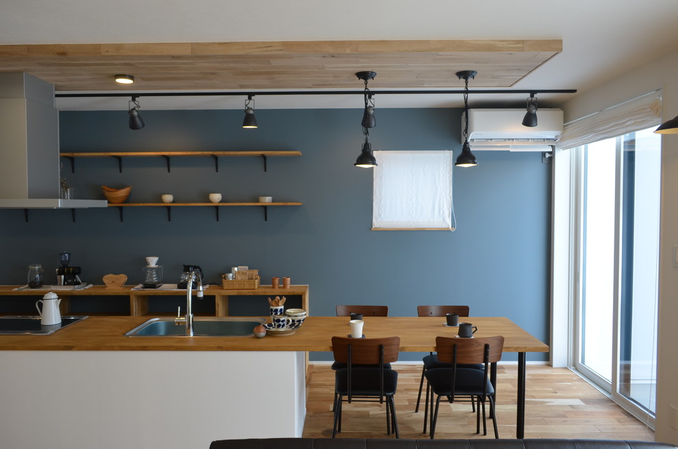 Immagine di una sala da pranzo aperta verso il soggiorno industriale di medie dimensioni con pareti blu, pavimento in legno massello medio, nessun camino e pavimento beige