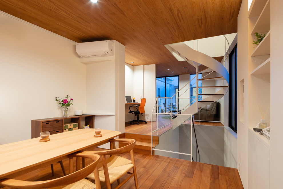 Inspiration pour une salle à manger ouverte sur le salon minimaliste avec un mur blanc, un sol en contreplaqué, aucune cheminée et un sol marron.