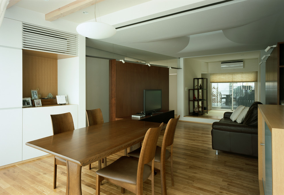Idées déco pour une salle à manger moderne avec un mur blanc, un sol en bois brun et un sol marron.