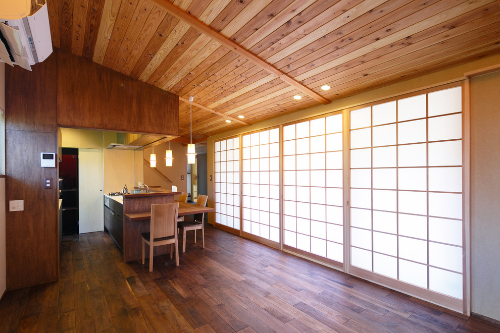 Cette photo montre une salle à manger ouverte sur le salon asiatique avec un mur beige, parquet foncé et un sol marron.